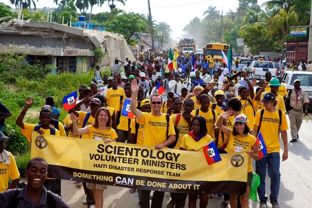 Scientology Pastorale Werkers uit Haïti en andere landen lopen mee in de mars van Port-au-Prince naar Léogane op de nationale vlaggetjesdag. De dag dat de onafhankelijkheid van Frankrijk uit 1803 wordt herdacht.
